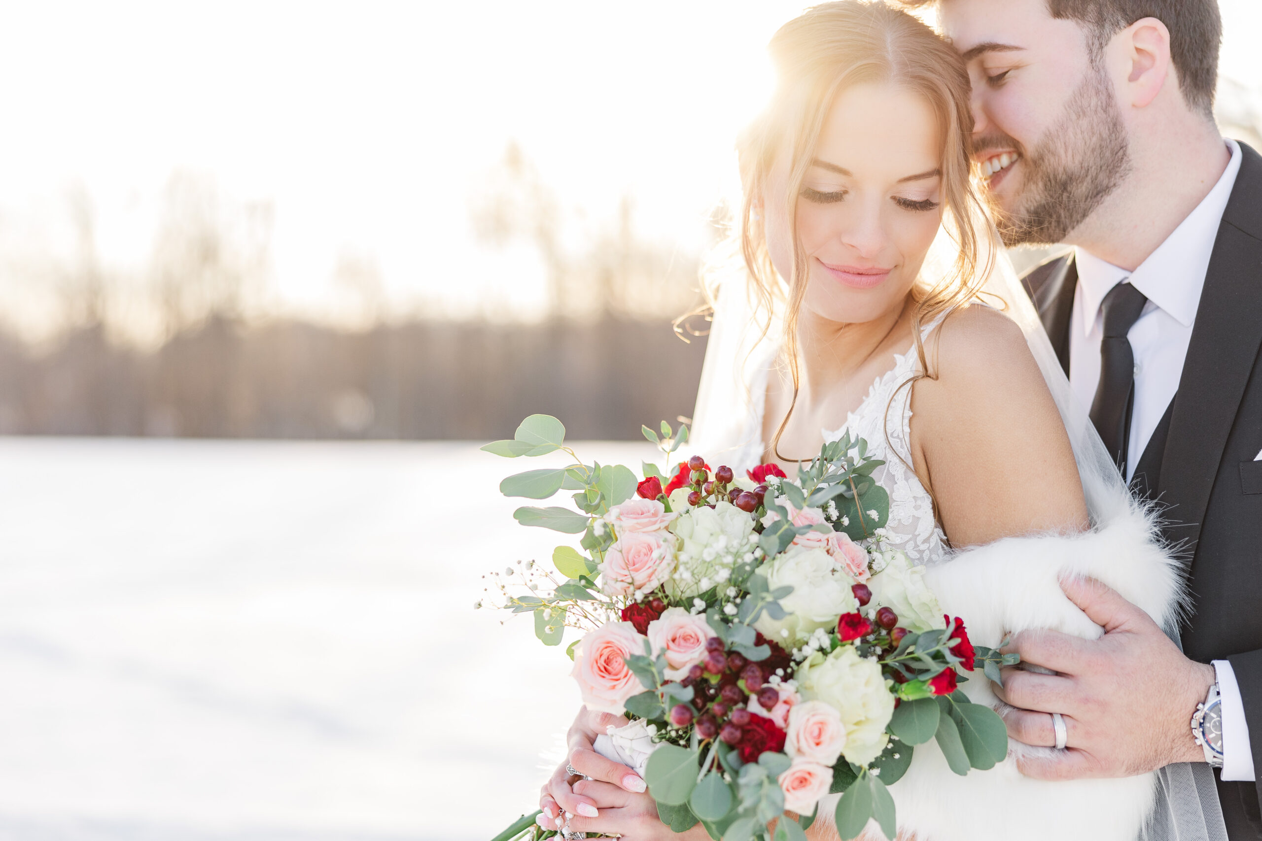 bride and groom embrace in winter during sunset